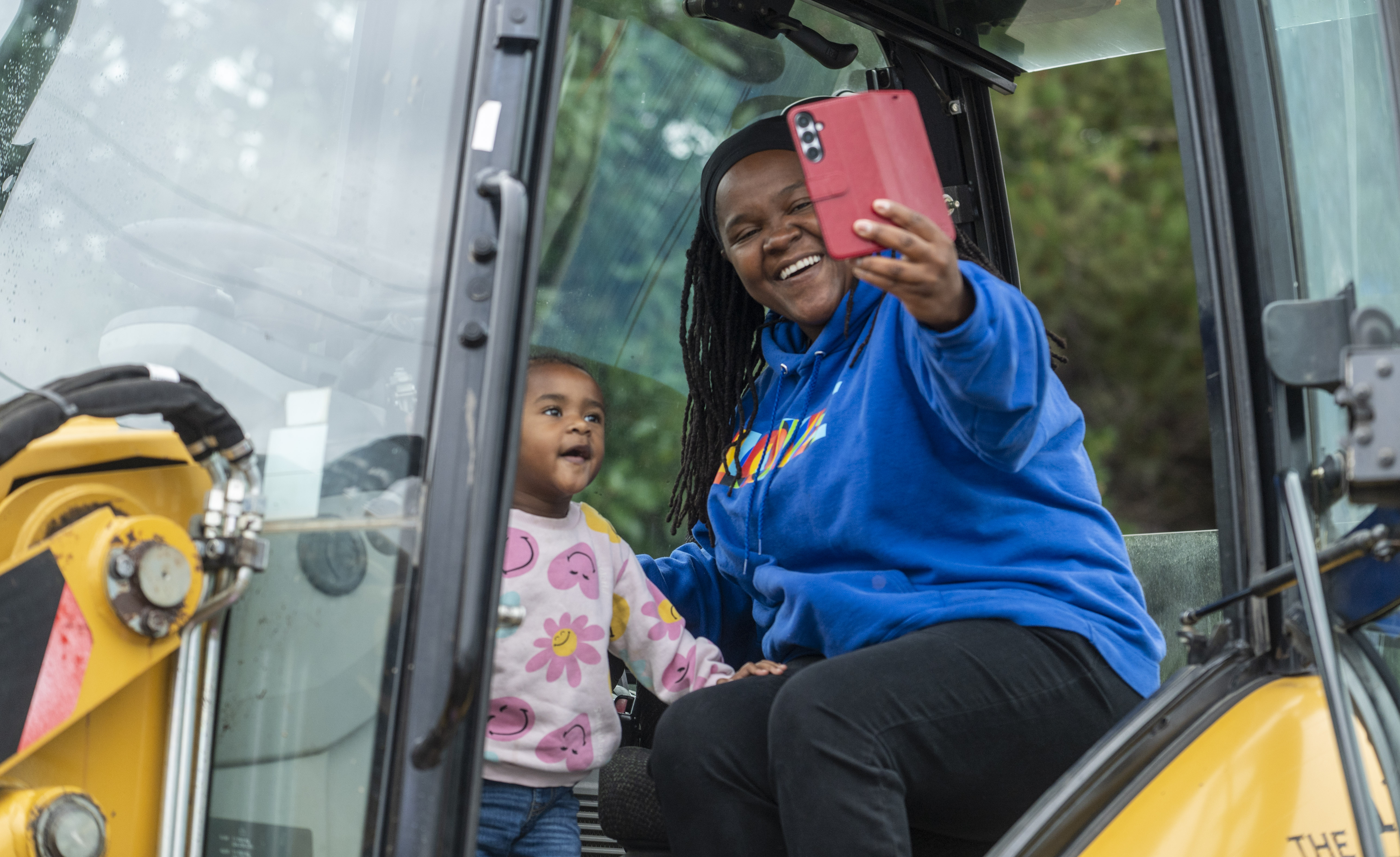A woman and small child take a selfie inside a construction vehicle.