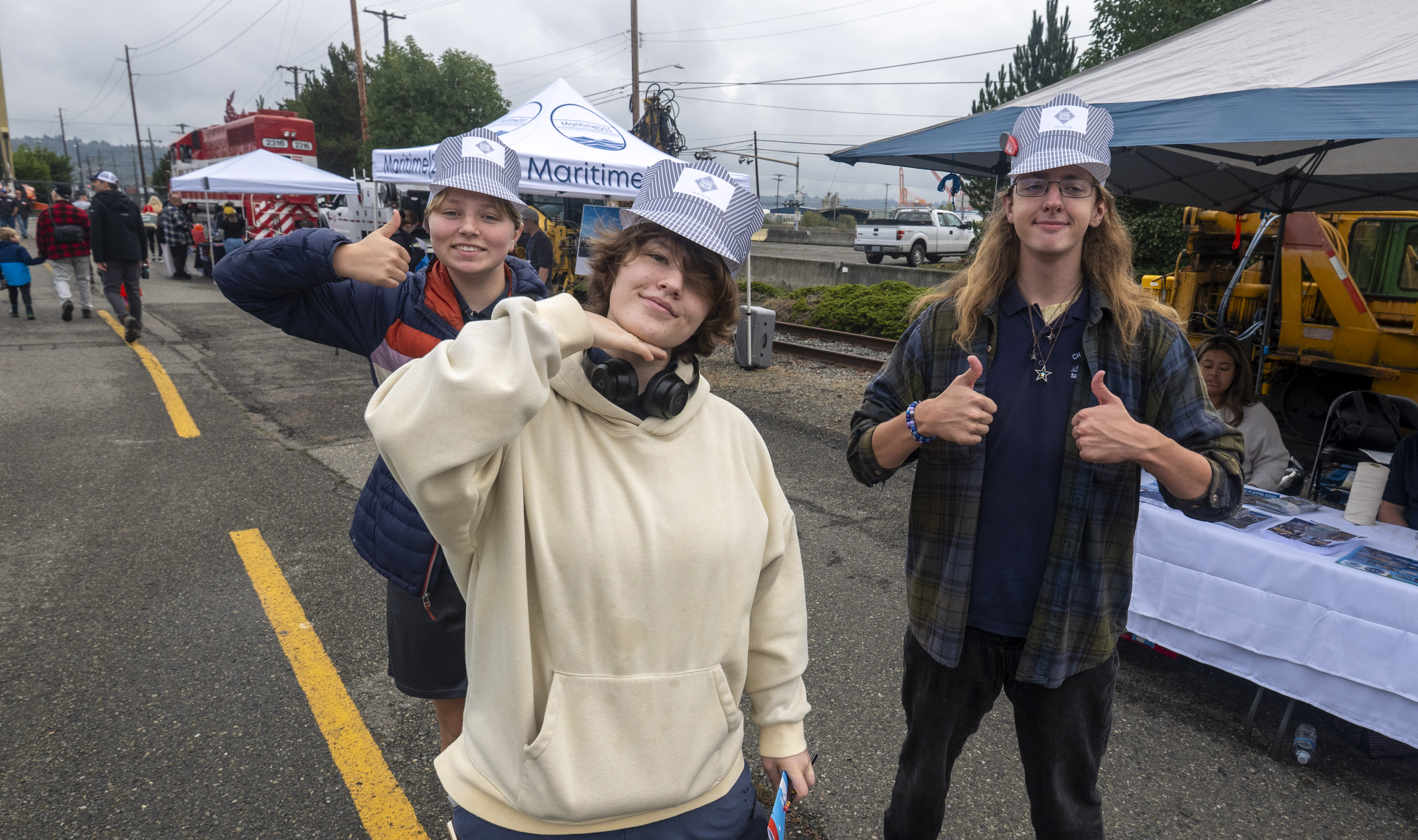 Three adolescents in train conductor hats pose for the camera.
