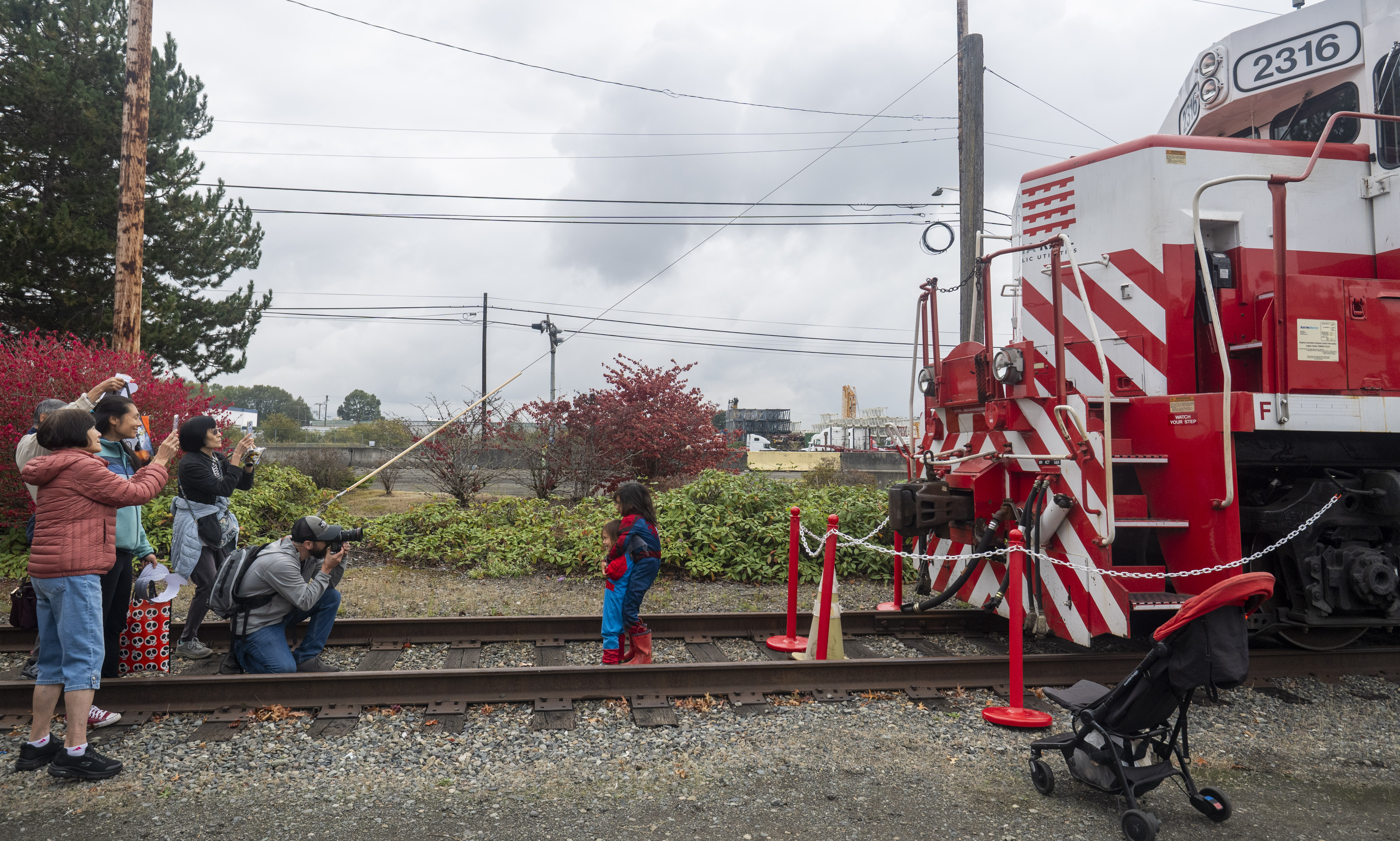 A child stands on a rail track next to a stationary train.