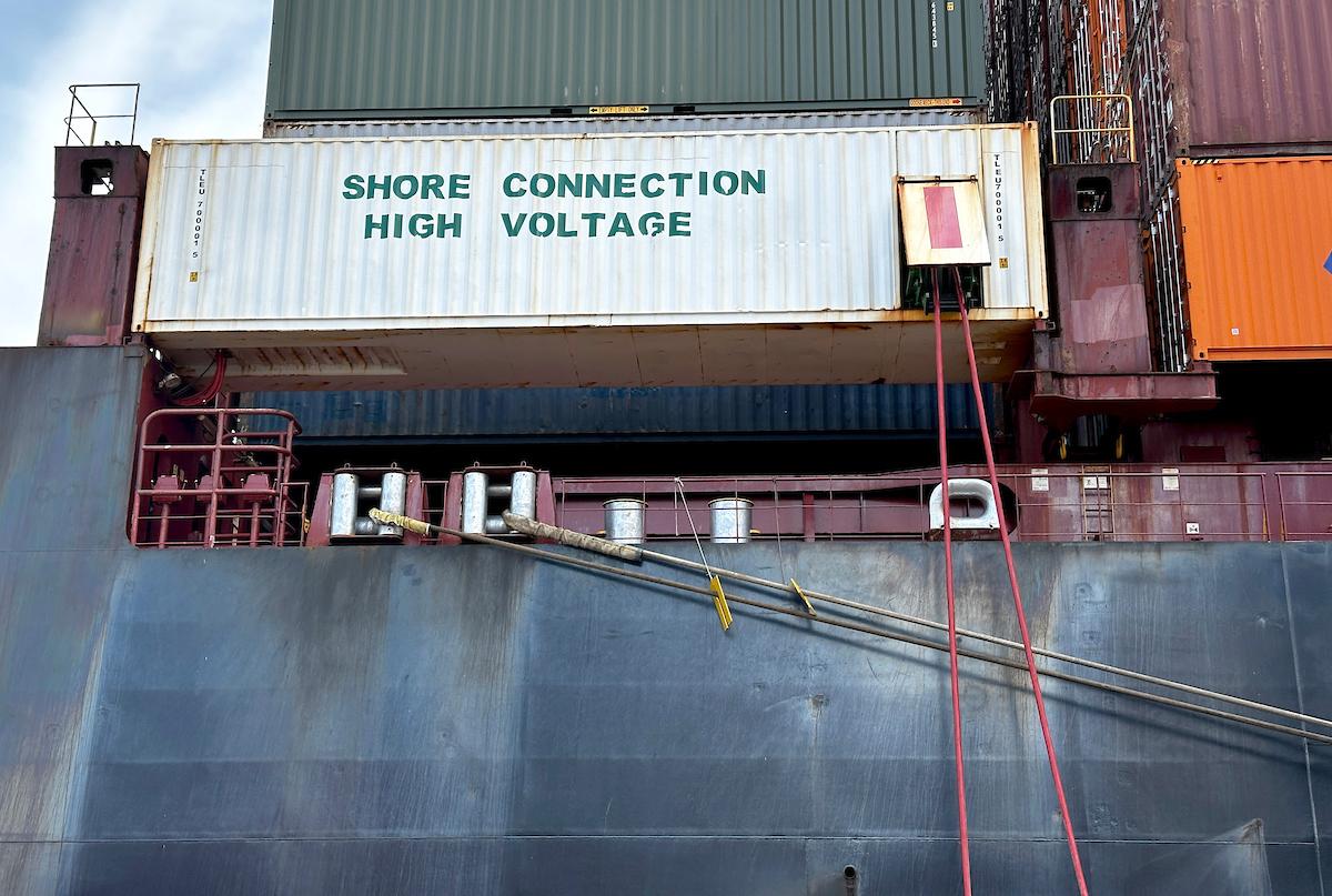A container on a ship with two cords coming out of a small door.